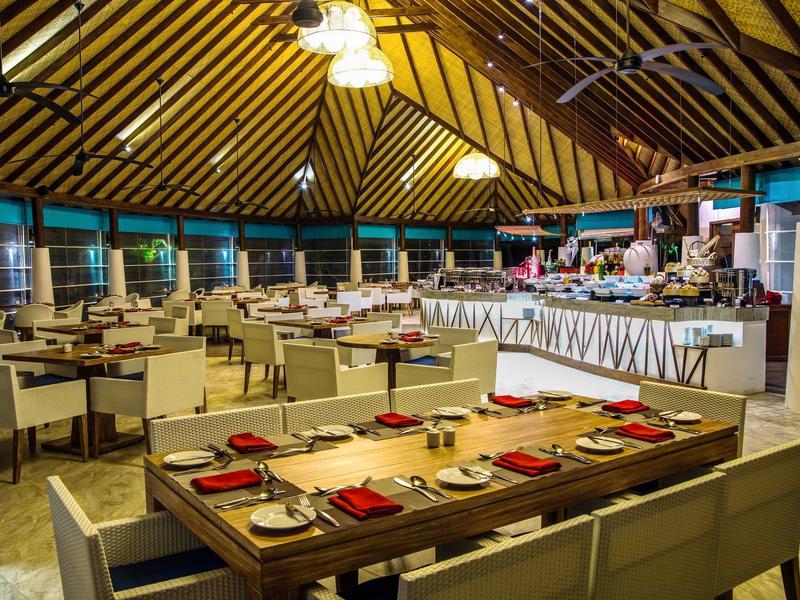 Großes Restaurant mit gedeckten Tischen und einem Buffetbereich unter einem Holzdach.