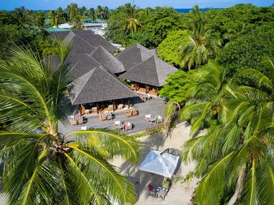 Panoramica di un complesso alberghiero tropicale con bungalow con tetto in paglia e palme.