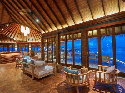 Accogliente salotto dell'hotel con interno in legno e vista sull'oceano di notte.