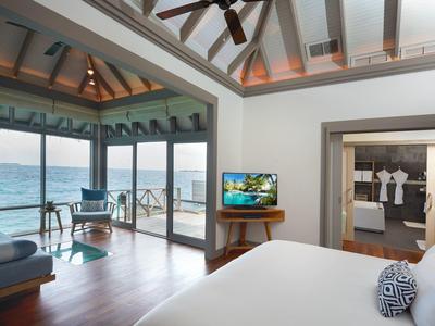 Luxuriöses Schlafzimmer mit Meerblick, Holzboden, Deckenventilator und angrenzendem Bad.