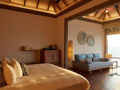 Camera d'hotel accogliente con letto grande, divano e vista mare attraverso le finestre.