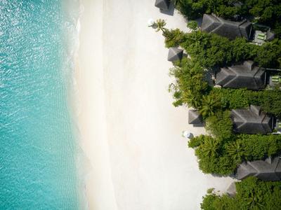 Vista aerea di una spiaggia di sabbia bianca con acqua turchese e case al margine della giungla.