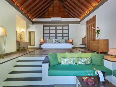 Helles Schlafzimmer mit Holzdecke, grüner Couch, Stufen und moderner Einrichtung.