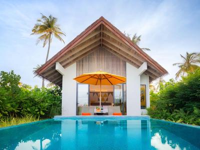 Nowoczesny bungalow z prywatnym basenem i parasolem, otoczony tropikalną roślinnością.