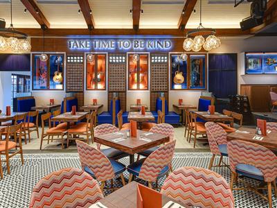 Gemütliches Restaurant mit Holzdecke, blauen Wänden, gemusterten Sesseln und großem Leuchtschild.