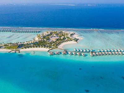 Insel mit tropischem Resort, blaues Meer, weiße Sandstrände und Wasserbungalows in Reihe.