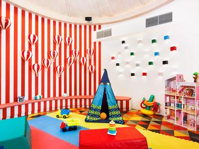 Buntes Kinderspielzimmer mit Zelt, buntem Teppich, Spielzeugautos und Regalen voller Spielzeug.