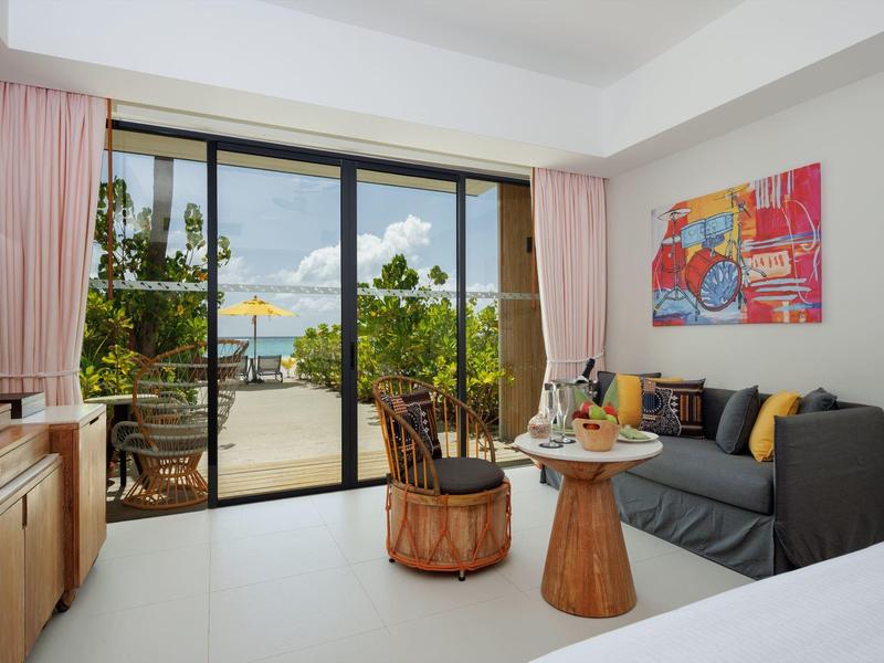 Helles Wohnzimmer mit grauem Sofa, runden Holztischen, Glas-Schiebetür und Blick auf Terrasse.