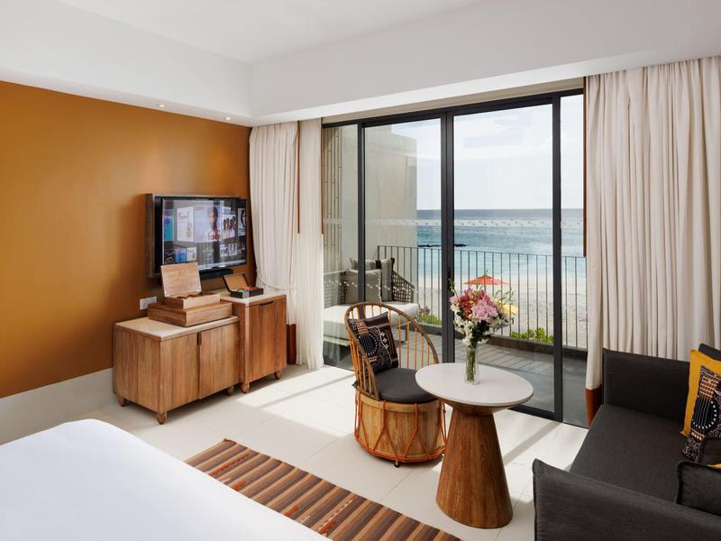 Modernes Wohnzimmer mit braunen Holzmöbeln, grauem Sofa und Balkon mit Meerblick.