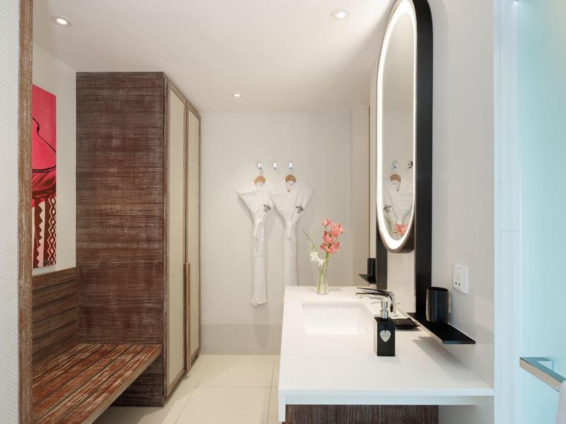 Moderne, helle Badezimmereinrichtung mit großem Spiegel, Waschbecken und Holzbank.