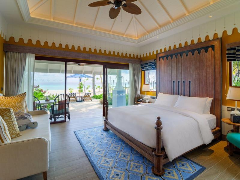 Elegancki pokój hotelowy z dużym łóżkiem i balkonem z widokiem na morze.