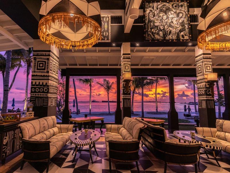 Luksusowy salon hotelowy z wygodnymi fotelami i widokiem na zachód słońca nad morzem.