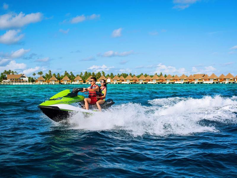 Person fährt mit grüner und weißer Jetski auf blauem Meer bei sonnigem Himmel.