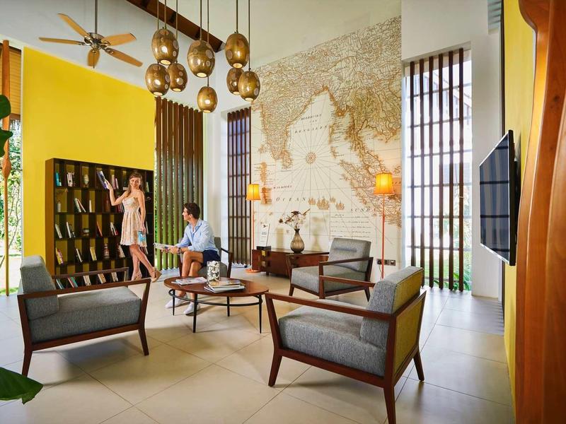 Moderner Wohnraum mit gelber Wand, Weltkarte, Holzmöbeln und großen Fenstern.