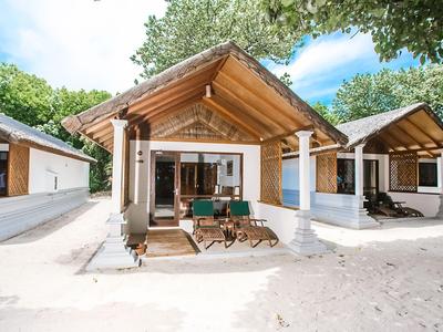 Bungalow indipendente con veranda e due lettini sulla spiaggia sotto gli alberi.