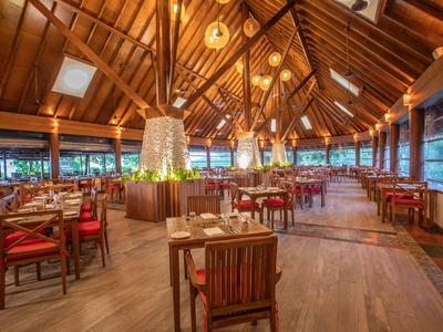 Elegant restaurant met houten dak, stoelen en warme sfeer in een tropisch resort.