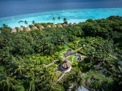 Luchtfoto van een resort met bungalows, zwembad en palmbomen aan de turquoise zee.