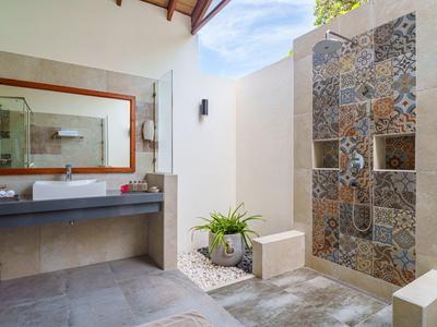 Moderne open douche met decoratieve tegels en planten in een lichte badkamer.