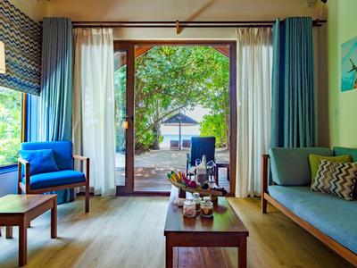 Gezellige woonkamer met blauwe stoelen, bank en groot raam met uitzicht op tuin.