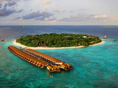Luchtfoto van een tropisch eiland met bungalows boven het water en helderblauwe oceaan.