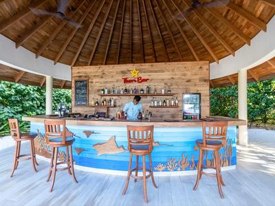 Open bar met houten krukken, tropische omgeving en rieten dak buiten