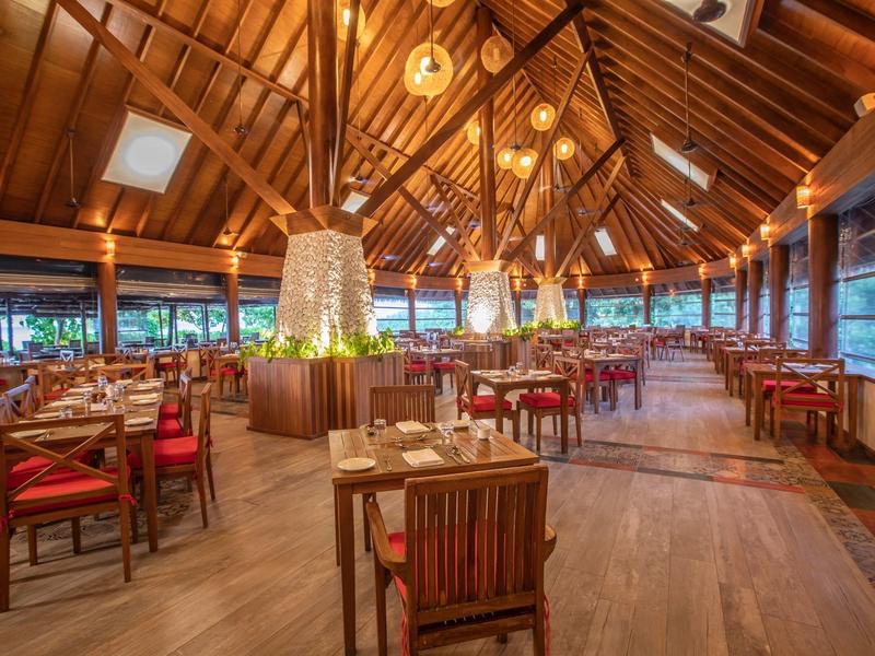 Elegant restaurant met houten dak, stoelen en warme sfeer in een tropisch resort.