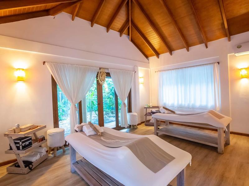 Gezellige behandelruimte met twee massagetafels en warm houten plafond.