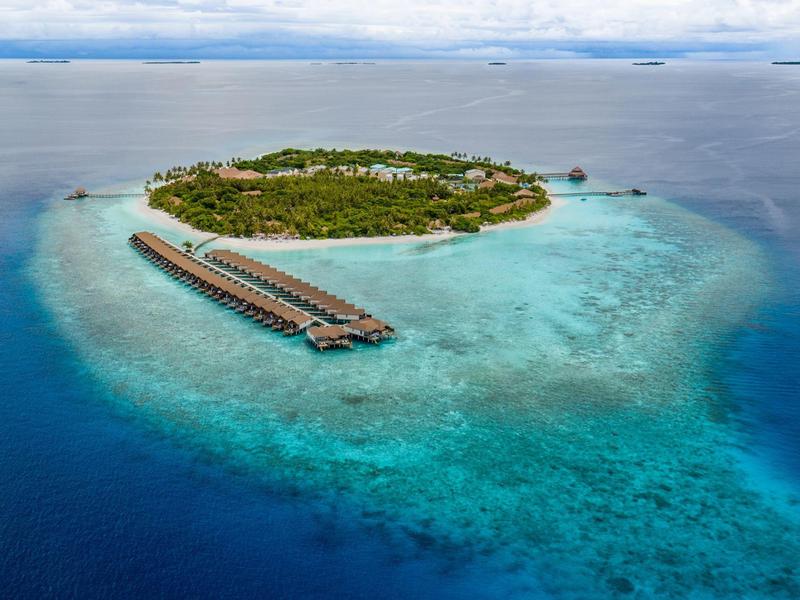 Luchtfoto van een tropisch eiland met watervilla's en helderblauwe zee.