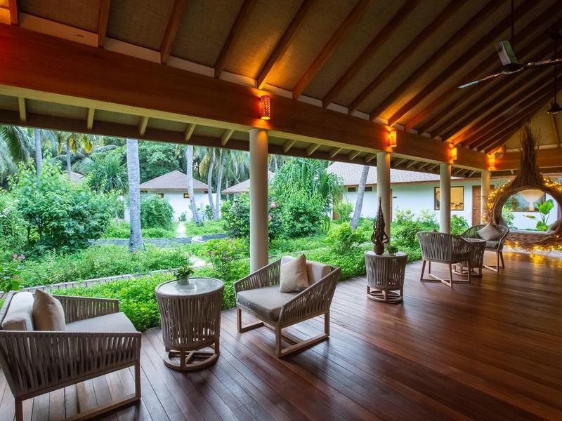 Overdekt terras met rotanmeubilair met uitzicht op weelderige tuin in een resort