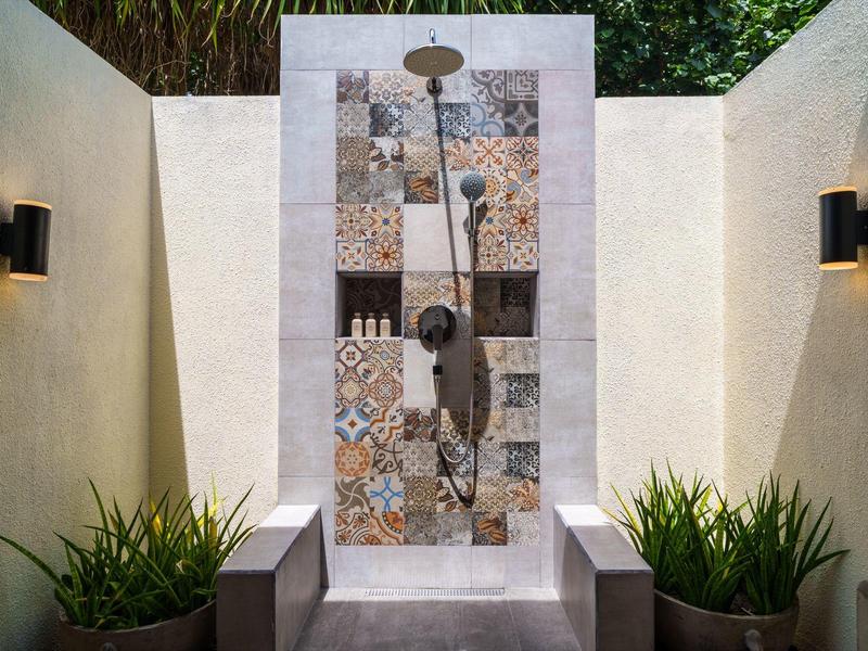 Moderne buiten douche met patroontegels en planten aan de zijkanten.