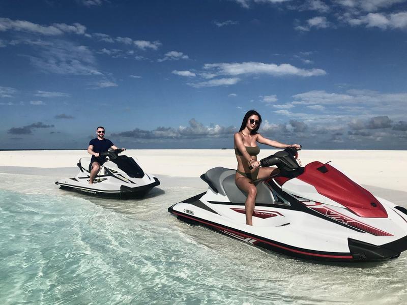 Twee mensen op jetski's in helder zee onder een zonnige hemel.