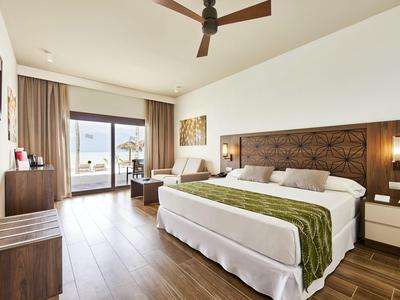 Modernes Hotelzimmer mit großem Bett, Holzboden und Blick auf Balkon und Meer