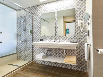 Modernes Badezimmer mit Doppelwaschbecken, dekorativen Fliesen und begehbarer Dusche.