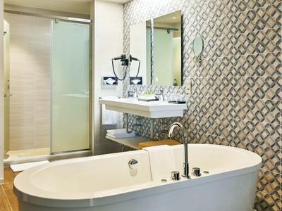 Modernes Badezimmer mit freistehender Badewanne und eleganter Fliesenwand.