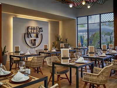 Ristorante moderno con arte murale decorativa e tavoli elegantemente apparecchiati.