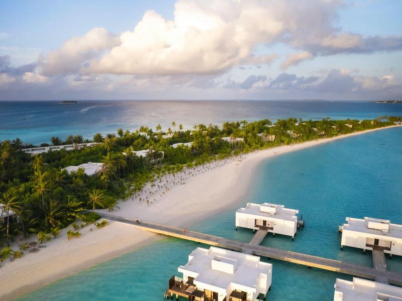 Tropische Insel mit weißem Sandstrand, Palmen und Überwasserbungalows im blauen Wasser.