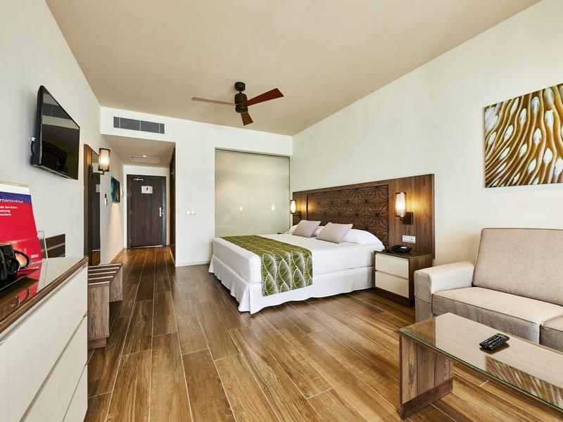 Modernes Hotelzimmer mit Doppelbett, Sofa, Holzboden und Wandbild.