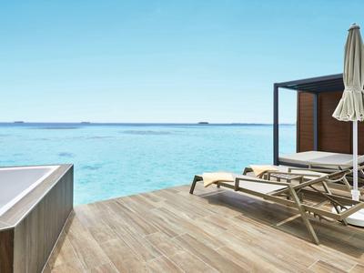 Luxuriöse Terrasse mit Whirlpool und Liegestühlen mit Blick auf türkisfarbenes Meer.