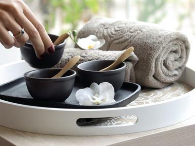 Ein Tablett mit Handtuch, schwarzen Schalen, Badesalz und weißen Blüten für Entspannung im Hotel