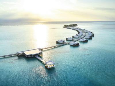 Luxuriöse Überwasser-Bungalows in einer Reihe über türkisfarbenem Meer bei Sonnenuntergang.