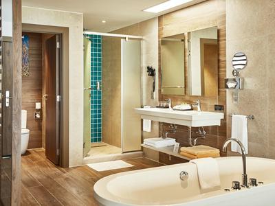 Modernes Badezimmer mit Badewanne, Dusche, Doppelwaschbecken und separater Toilette in warmen Tönen.