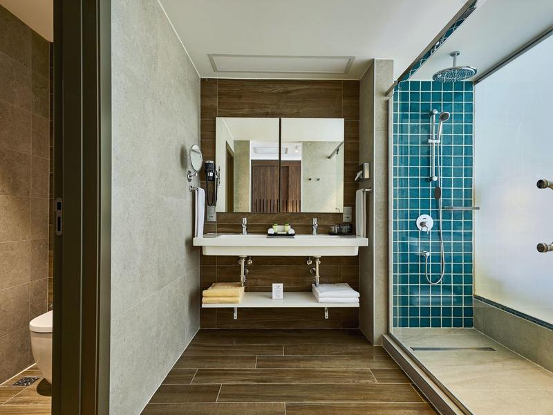 Modernes Badezimmer mit Doppelwaschbecken, Holzfußboden und blauen Fliesen in der Dusche.