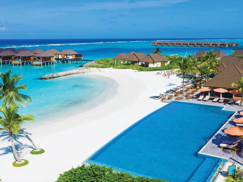 Tropisches Resort mit weißem Sandstrand, türkisfarbenem Meer, Palmen und langem Infinity-Pool.