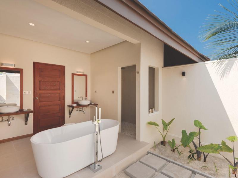 Moderner Badbereich mit freistehender Badewanne, zwei Waschbecken, Holzdekor und hellen Wänden.