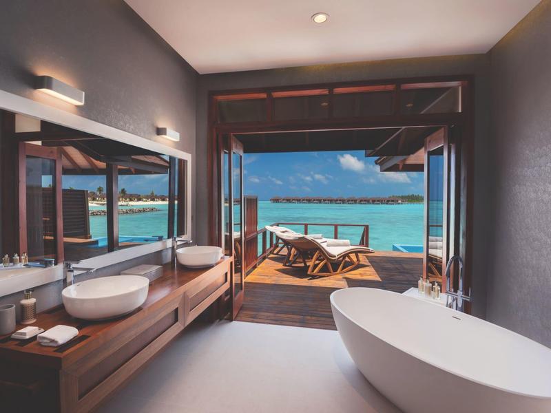 Modernes Badezimmer mit freistehender Badewanne, zwei Waschbecken und Blick auf Meer und Terrasse.