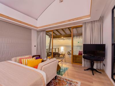 Modern eingerichtetes Schlafzimmer mit Doppelbett, Sofa, Flachbildfernseher und Zugang zur Terrasse.