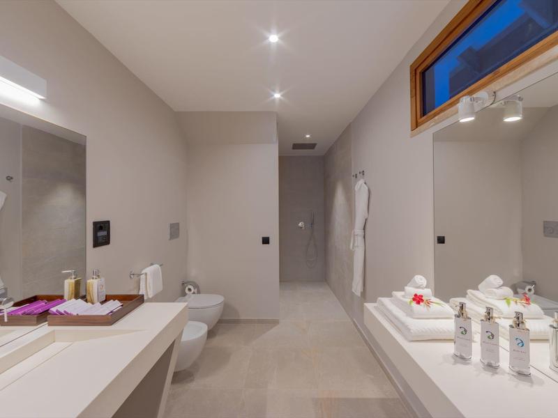 Modernes Badezimmer mit beiger Farbgebung, Doppelwaschbecken, WC und großer Dusche.