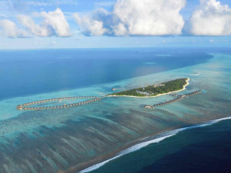 Kleine tropische Insel mit Sandstrand, türkisfarbenem Wasser und über Wasser gebauten Bungalows.