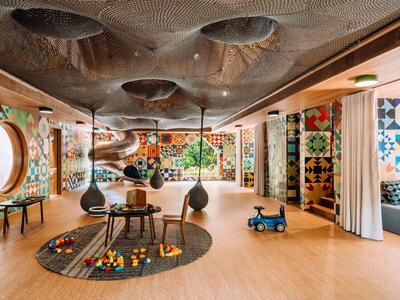 Bunter Kinderspielraum mit Holzfußboden, Spielzeug und Fenster mit Rundfenstern.