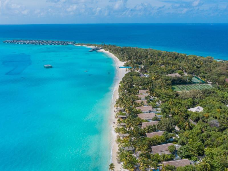 Insel mit türkisblauem Wasser, weißem Sandstrand und grüner Vegetation entlang der Küste.